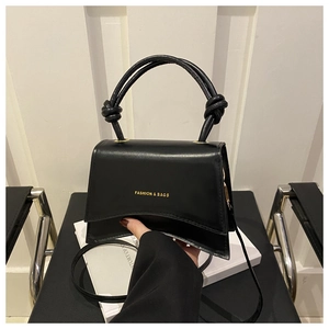 Detail of black glossy handbag with unique curved base and gold FASHION & BAGS lettering