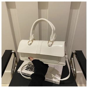 Detail of white glossy leather handbag with rectangular flap and metal hardware on a chair