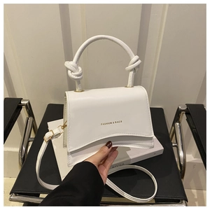 Close-up of white PU leather crossbody bag with knot handle and gold text detail