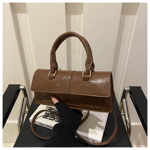 Detail of a dark brown vintage oil wax leather handbag with golden metal hardware and strap