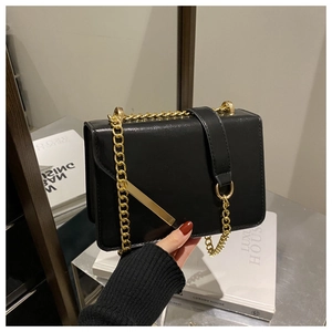 Detail of elegant black leather chain bag with polished gold-tone hardware and flap closure