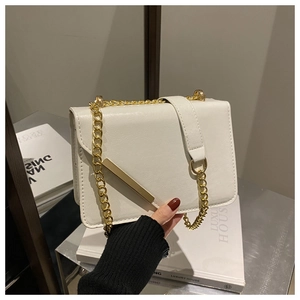 Close-up of white leather crossbody bag with gold chain strap and metal bar detail