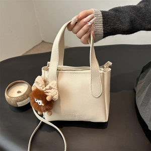 Fashionable cream bucket bag with lychee grain texture and cute plush monster charm