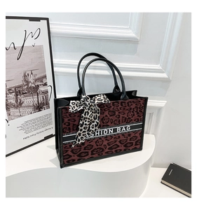 Détail du cabas léopard rouge avec sangle tendance et foulard noué sur l'anse