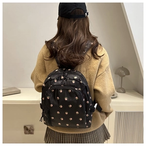 Detailed view of a small black floral backpack with adjustable straps on a model back