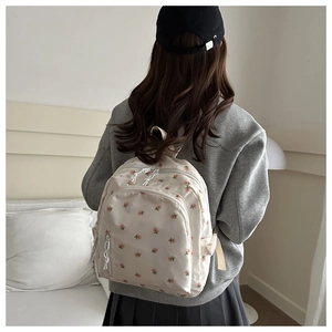 Detailed side view of floral student backpack worn by a model in a minimalist room