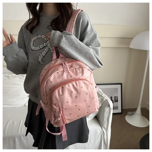 Detail of pink floral nylon backpack featuring multiple zip compartments in cozy room