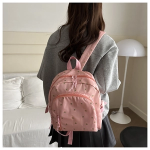 Detailed back view of a mini pink floral backpack on model in a soft indoor setting