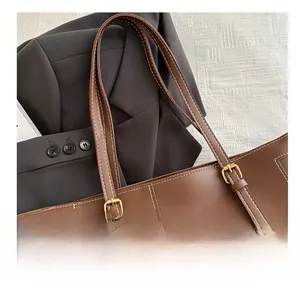 Detail of brown faux leather tote with white stitching and adjustable gold buckle strap