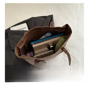 Interior storage capacity view of brown tote bag with white stitching and personal items