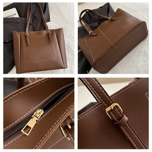 Detail of brown tote bag featuring white contrast stitching and gold metal hardware