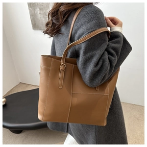 Detail of camel tote bag with white contrast stitching on grey wool coat background