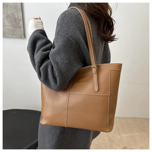 Detail of khaki tote bag with distinctive white contrast stitching and adjustable strap