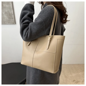 Detailed view of beige leather tote bag with white stitching and adjustable strap