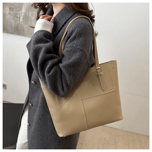 Detail of khaki leather tote bag with white stitching and metal buckle on shoulder strap