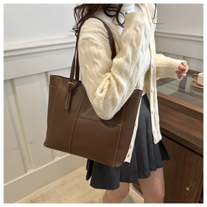 Close-up of brown tote bag showing contrast stitching and metal buckle details