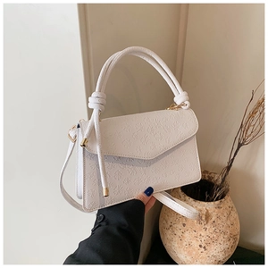 Vue macro d'un sac bandoulière en cuir blanc avec gaufrage trèfle à quatre feuilles