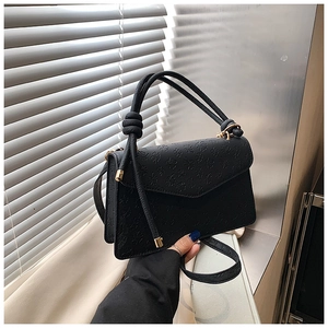 Detail of black crossbody bag with clover embossed pattern and knotted handle
