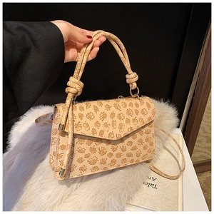 Detail of embossed floral texture on beige handbag with stylish knotted handle