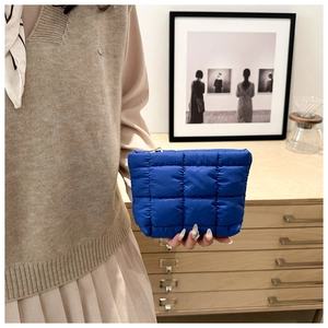 Detail of royal blue quilted makeup bag with square texture and metal zipper closure