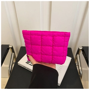 Close-up of rose red quilted grid makeup bag held in hand for size comparison