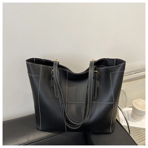 Detail of contrast stitching on a large black leather tote bag with gold buckles