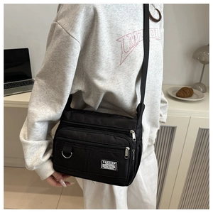 Detail der wasserdichten Nylon-Umhängetasche mit Multi-Pocket-Design und Silber-Reißverschlüssen