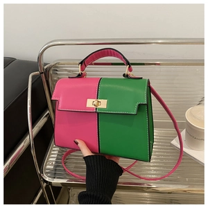 Detail view of pink and green color-block handbag with gold twist lock and white stitching
