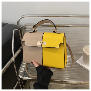 Detail of two-tone Kelly style handbag with gold twist lock and adjustable strap