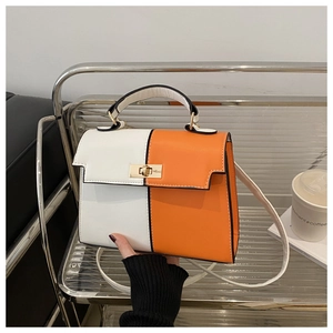 Detail of two-tone Kelly bag in orange and white with gold rotating metal lock