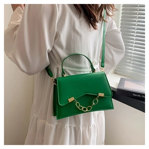 Gros plan d'un sac à main en cuir vert avec une chaîne dorée épaisse et une bandoulière