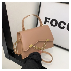 Détail du sac boîte beige avec rabat géométrique et grosse chaîne métallique dorée
