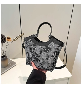 Detailed side view of black silk embroidery bucket bag with floral patterns and leather strap
