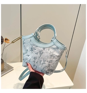 Detail of light blue floral jacquard texture and leather handles on bucket tote bag