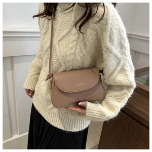 Close-up of khaki retro crossbody bag featuring golden fashion text and knot detail