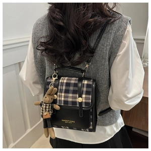 Detail view of British style plaid backpack with a cute knitted bunny charm accessory