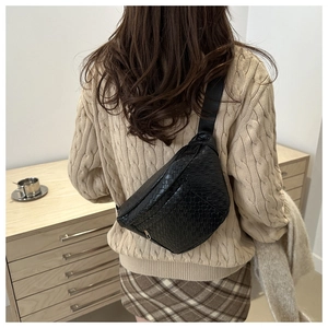 Close-up of black woven texture on fashionable crossbody chest bag with adjustable strap