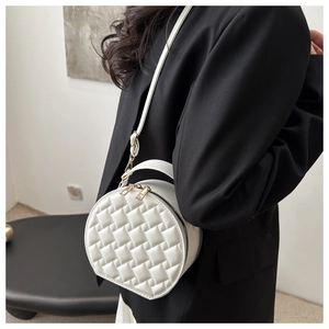 Detail of white woven crossbody bag paired with a black blazer for a modern minimalist look