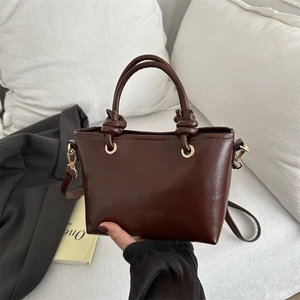Sac à main marron foncé brillant avec poignées nouées et œillets dorés