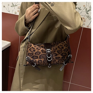 Detail of leopard print shoulder bag with silver metal buckles and brown leather trim