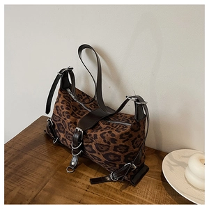 Detail of leopard print tote bag with leather straps and silver buckles on wood table