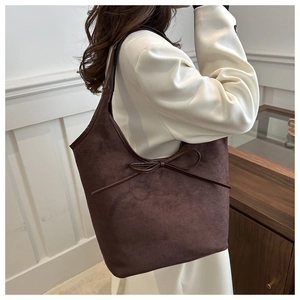 Gros plan du sac cabas marron mat avec un nœud en cuir et une texture en daim fin