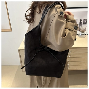 Détail d'un grand cabas noir mat avec nœud, porté avec un trench-coat classique chic
