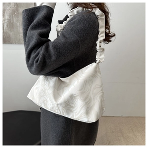 Detailed view of grey marble pattern handbag with pleated ruffle shoulder strap on coat