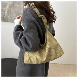 Close-up of mustard green satin pleated bag with marble pattern and ruffled shoulder strap