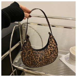 Detail of leopard print crescent bag with leather strap and zipper in a lifestyle setting