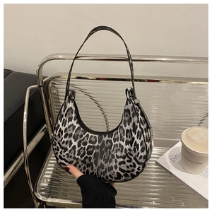 Detail shot of chic leopard print crescent bag with black zipper on a metal chair