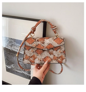 Detail of faux snakeskin crossbody bag featuring orange geometric pattern and rope knot handle