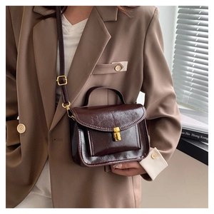 Détail du sac messager vintage marron avec fermoir doré et bandoulière réglable