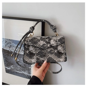 Detail of snake print leather bag with knotted handle and elegant gold hardware clasp
